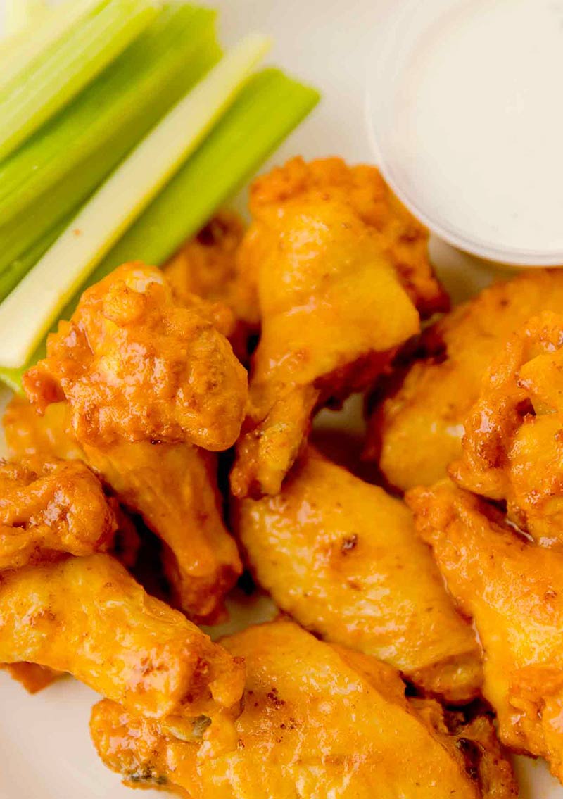 close up of traditional chicken wings with ranch and celery