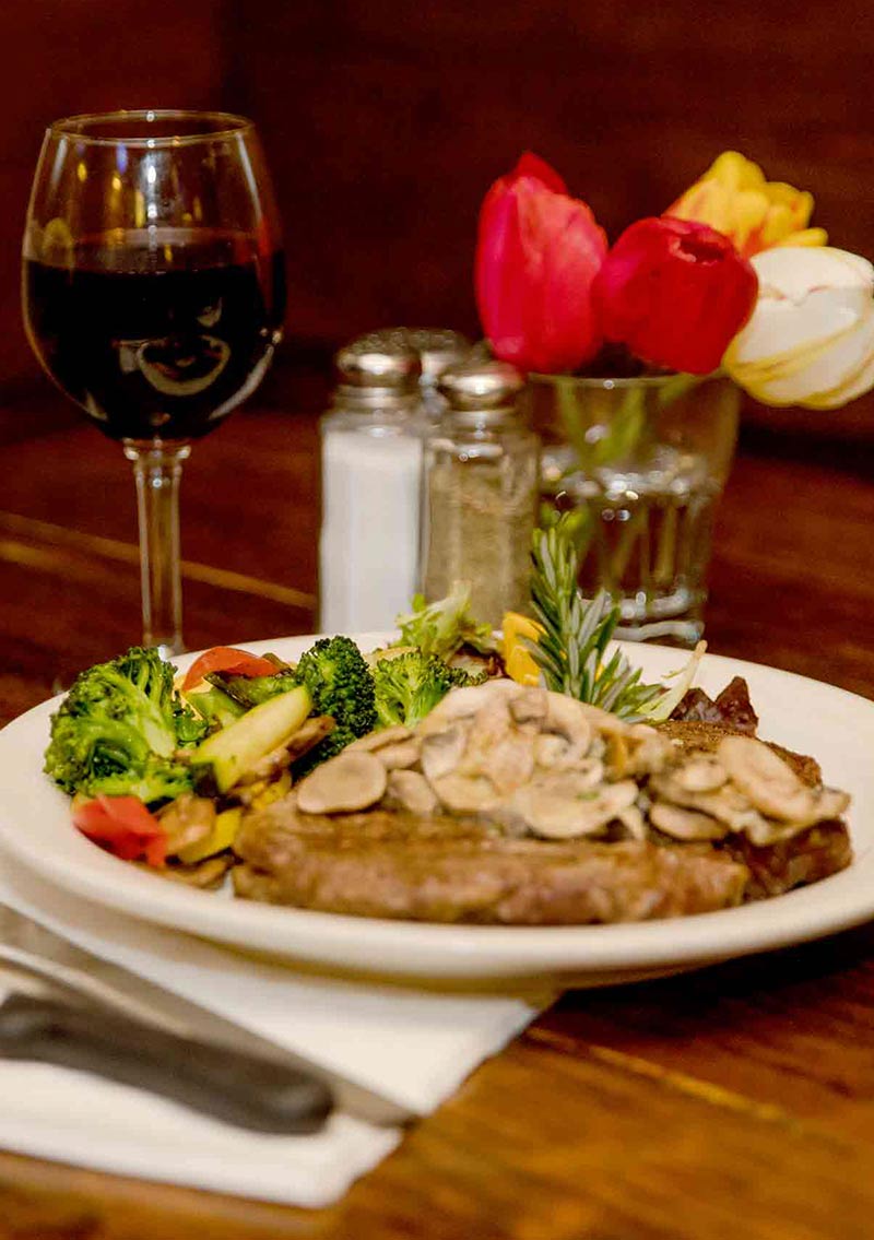 wine steak and veggies on a wood table