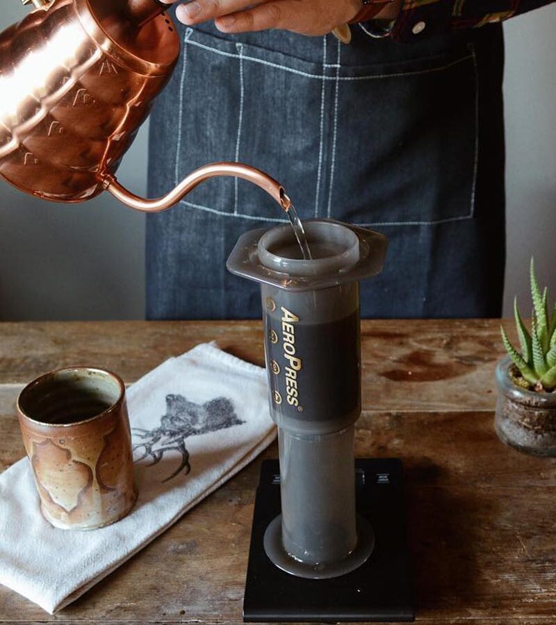 barista pouring hot water into a aeropress