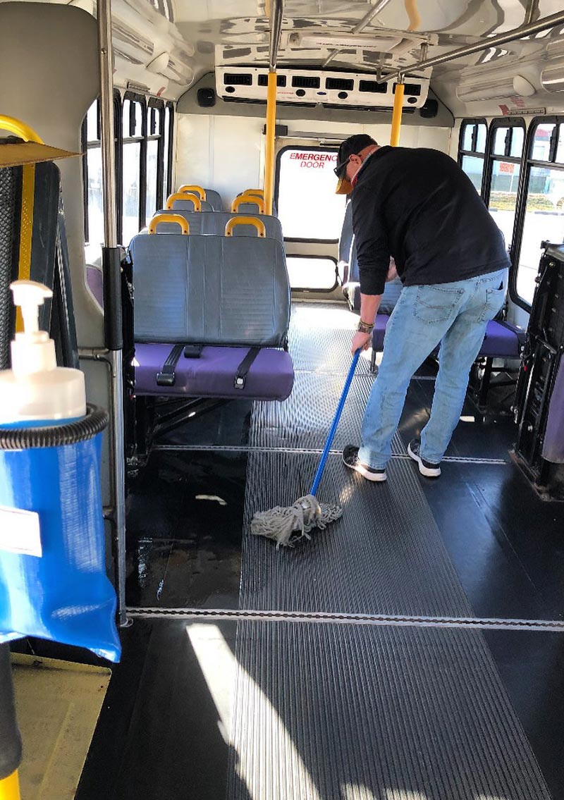 man mopping interior of bus