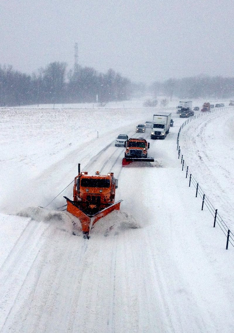 two snowplows plowing the way for traffic on snowy road