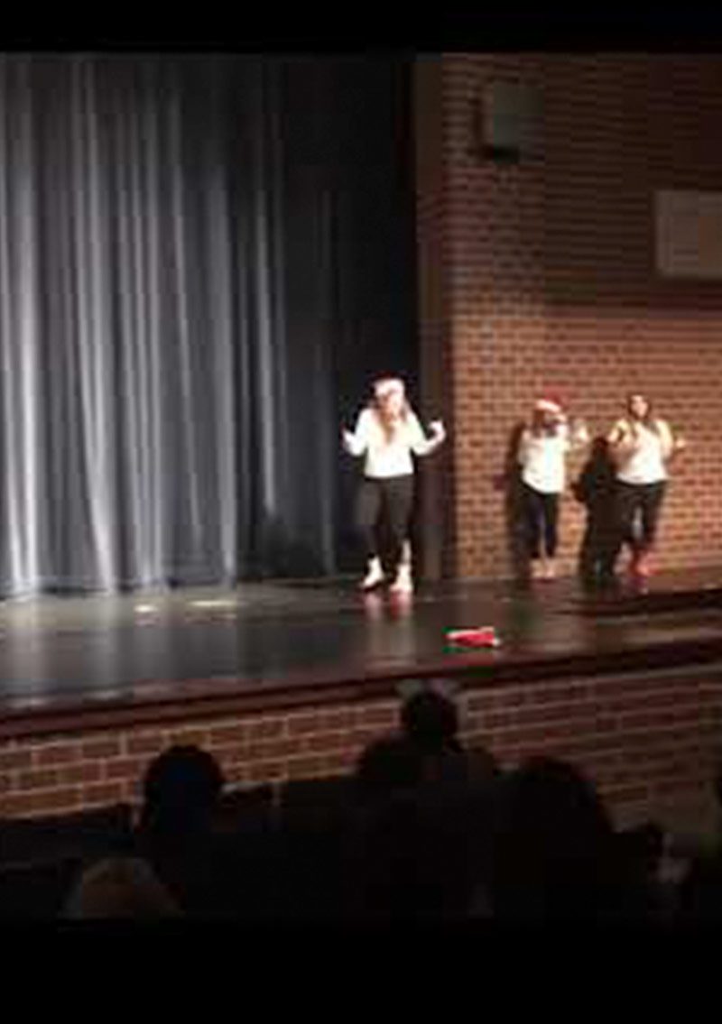 high school performers on stage wearing white shirts and black pants