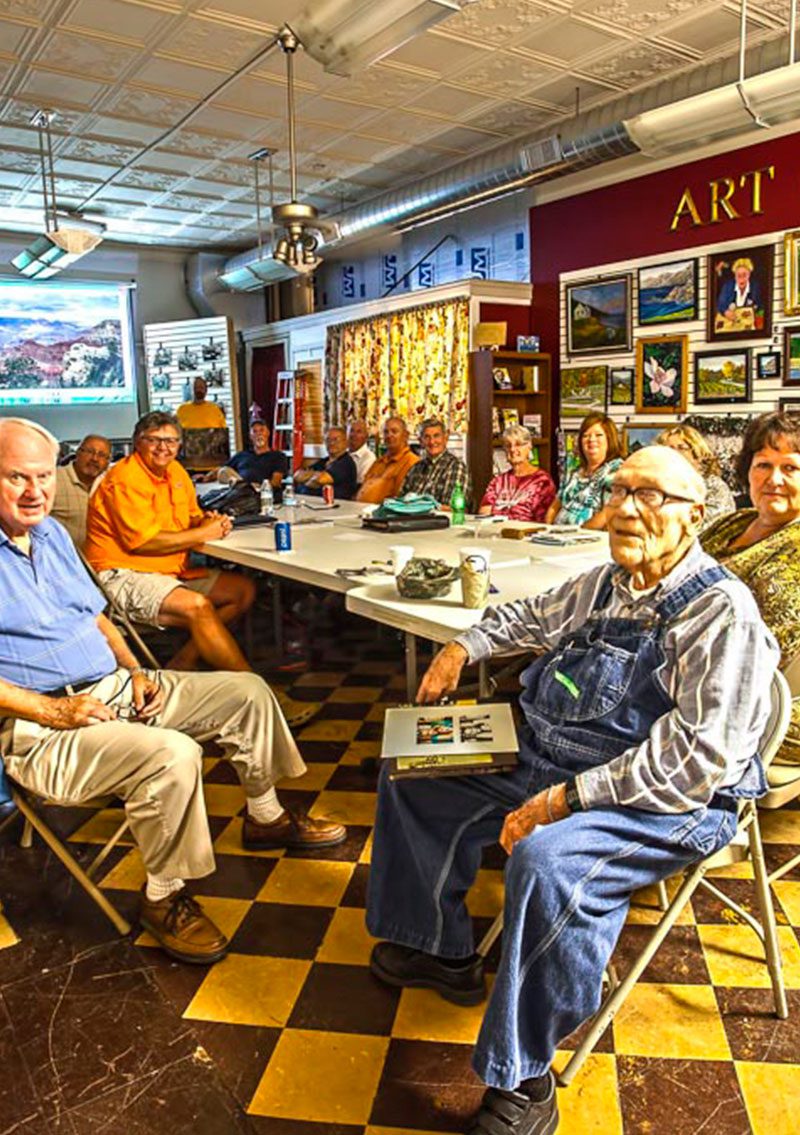 old folks sitting at a plastic white fold out table posing for camera