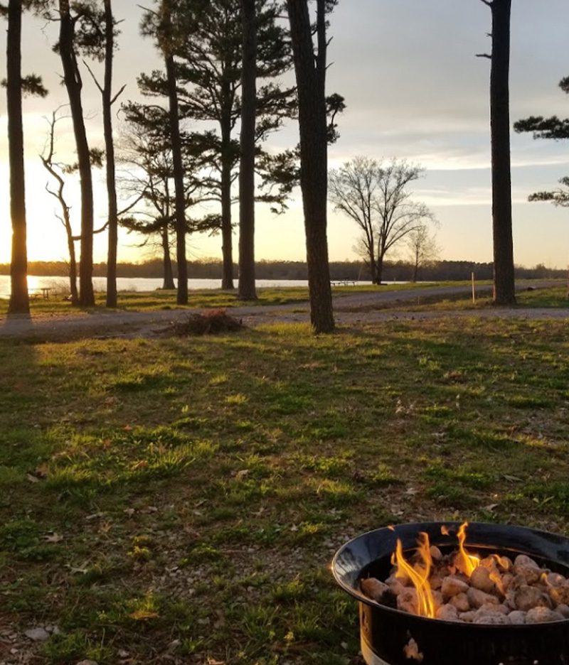 campground with sunset in background with grill campfire in foreground