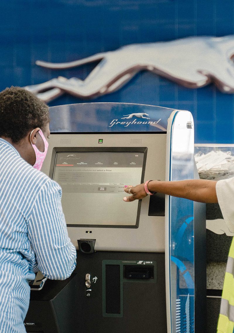 passenger looking at digital kiosk and selecting her ticket