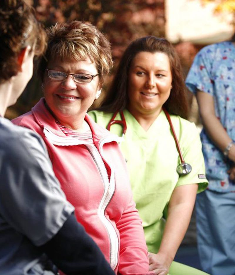 nurses and patients in scrubs smiling at photographer