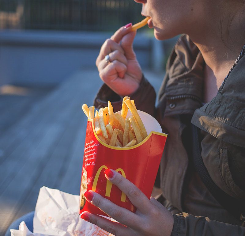 person sitting on bench eating mcdonalds fries